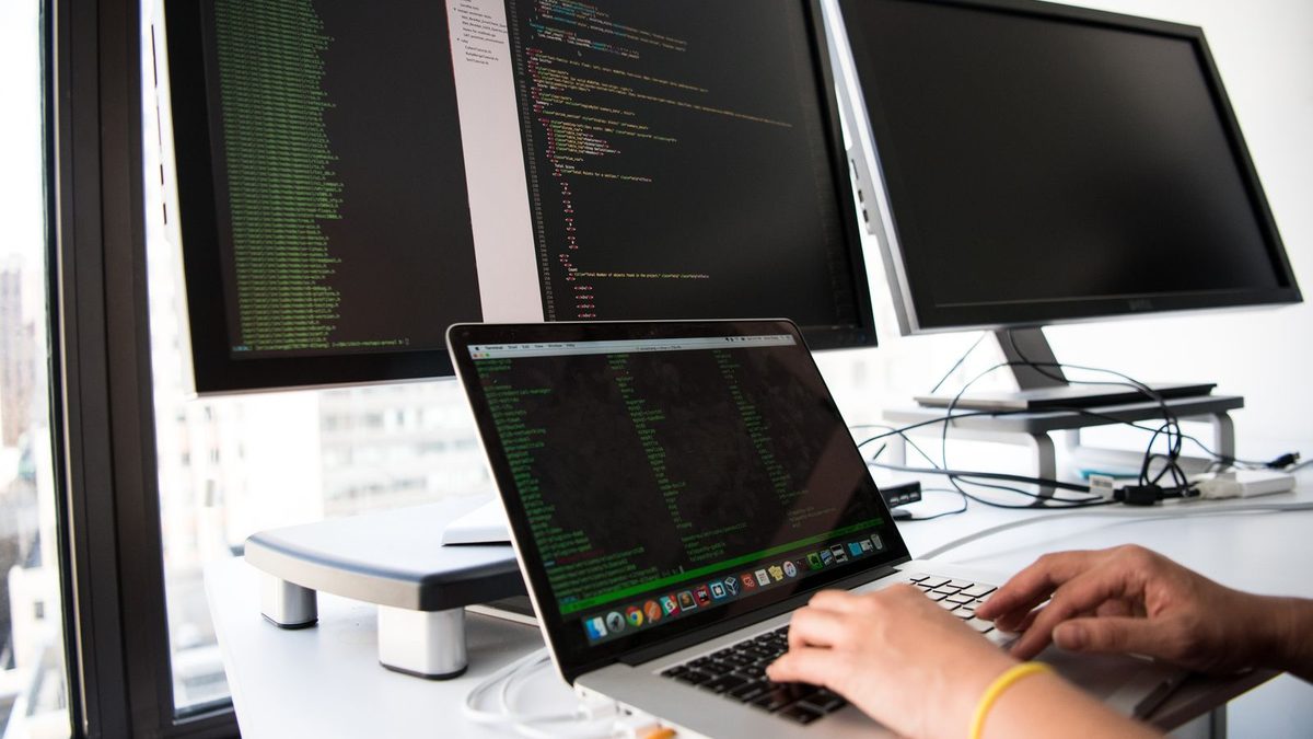 Hands typing code on a laptop